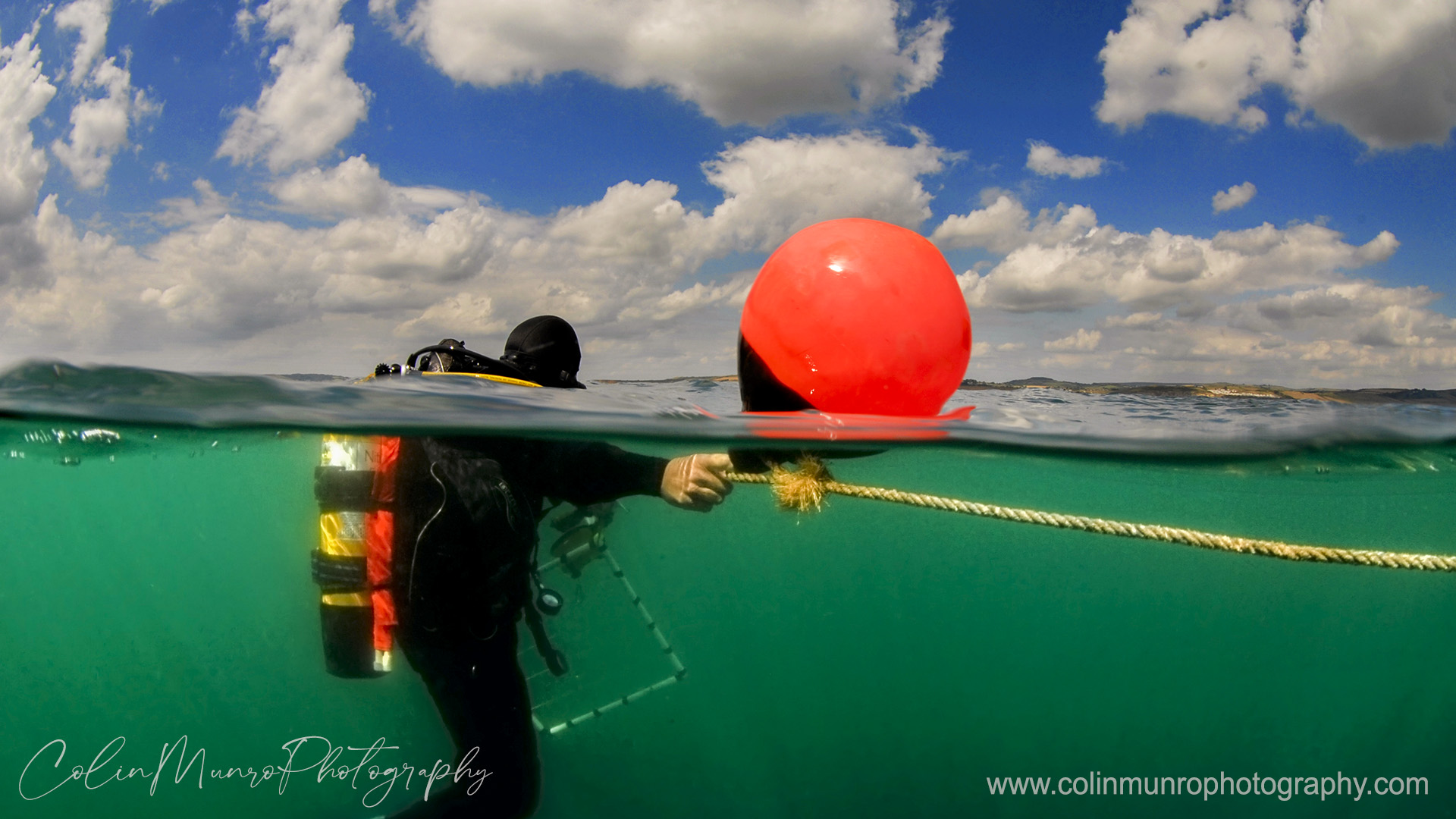 A scientific diver hangs on to a buoy line at the end of a dive. Lyme bay, English Channel. A half and half split shot, over under, by Colin Munro Photography